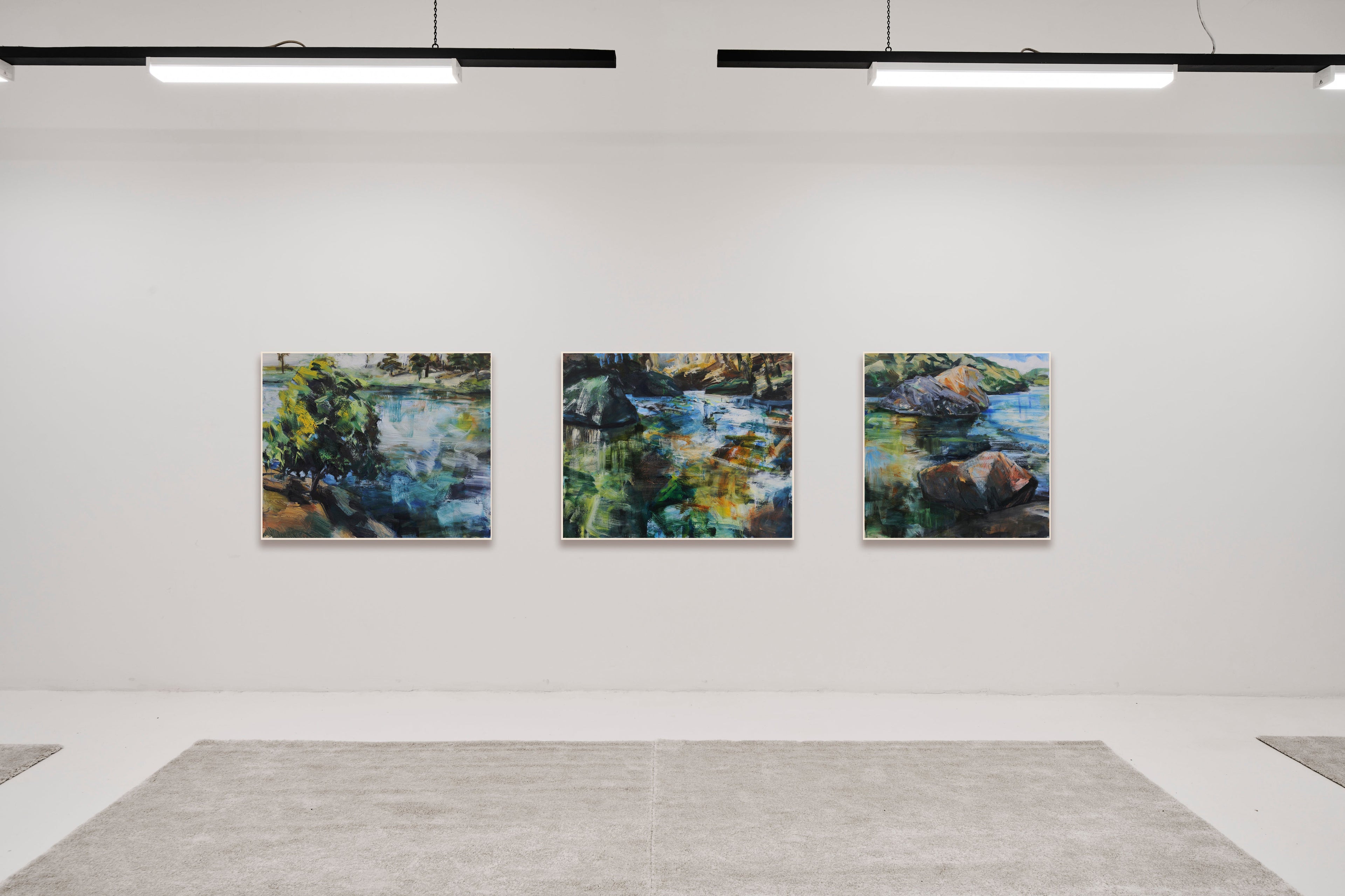 Exhibition install image with three landscapepaintings